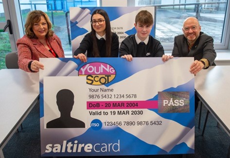 Transport Secretary Fiona Hyslop and Active Travel Minister Patrick Harvie pose with schoolchildren behind a large mocked up Young Scot NEC card