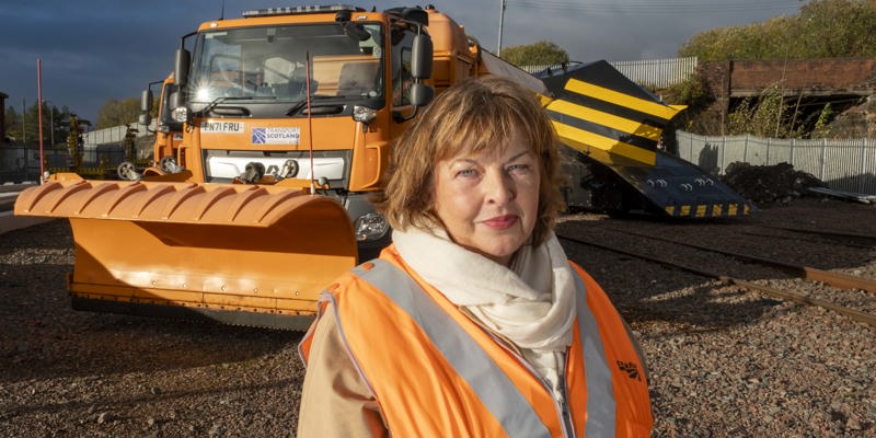 Transport Secretary Fiona Hyslop poses for a photo in front of a gritter and a snow plough train.