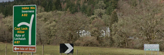 Green primary route direction sign on the northbound A82 at Invergarry, including direction to Kyle of Lochalsh  (with Gaelic version in yellow text). Brown tourist sign to Isle of Skye has been installed beneath the green sign, with no Gaelic version.